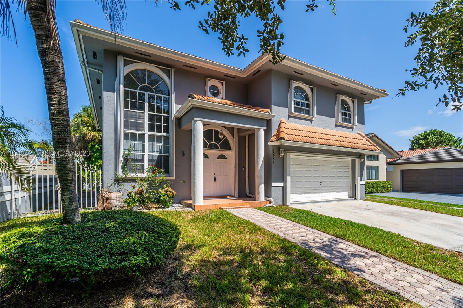 A two-story gray house with a tiled roof, arched windows, and a paved walkway — 15251 NW 89th Ave, Miami Lakes FL 33018, MIAMI LAKES, FL