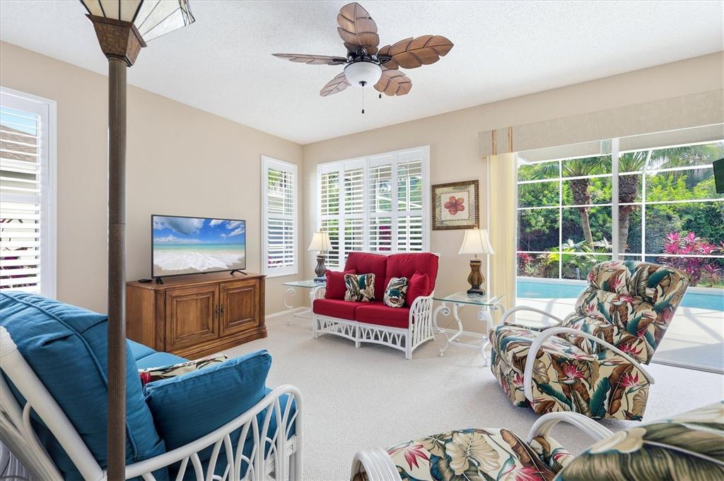 A living room features white wicker furniture, a red sofa, and a view of a pool — 5159 51ST LANE W, BRADENTON, FL