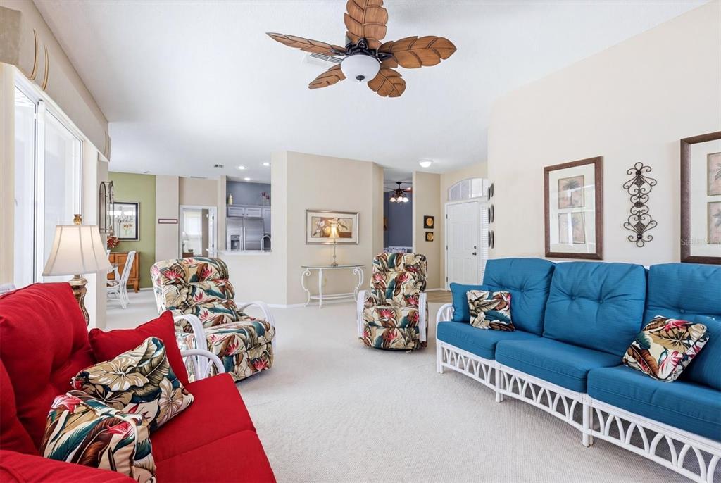 A living room features a blue sofa, a red sofa, floral armchairs, and a ceiling fan — 5159 51ST LANE W, BRADENTON, FL