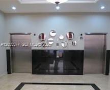 A lobby area features two stainless steel elevator doors flanking a black console with circular mirrors — CORAL GABLES, FL
