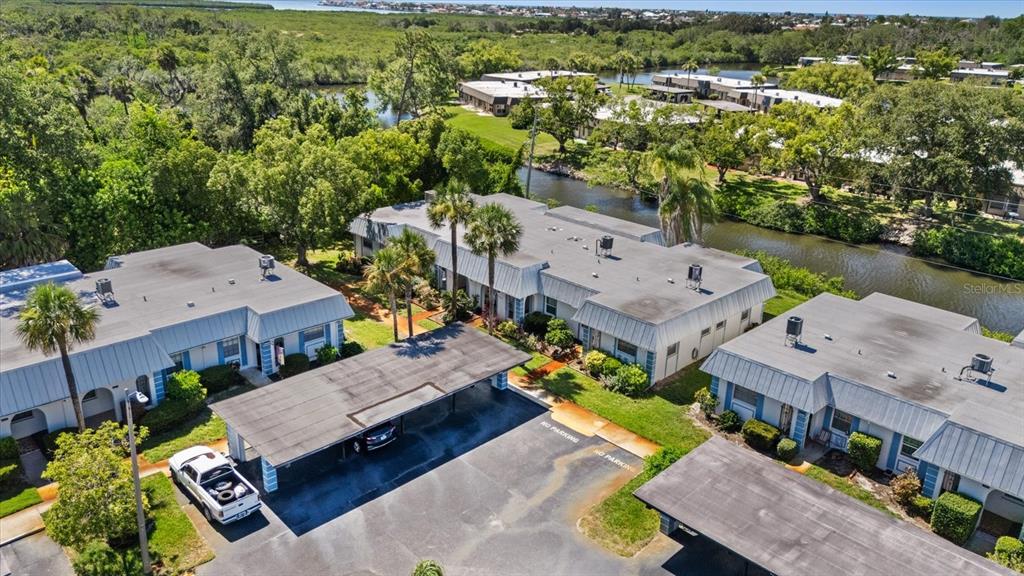 An aerial view shows several single-story apartment buildings with metal roofs and covered parking spaces — 4243 RICHMERE DRIVE UNIT 3B, NEW PORT RICHEY, FL
