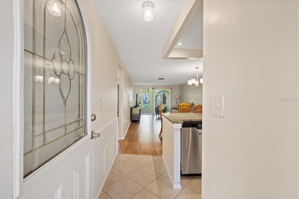 An entryway with tile flooring leads into a living area with wood-style floors — 4243 RICHMERE DRIVE UNIT 3B, NEW PORT RICHEY, FL