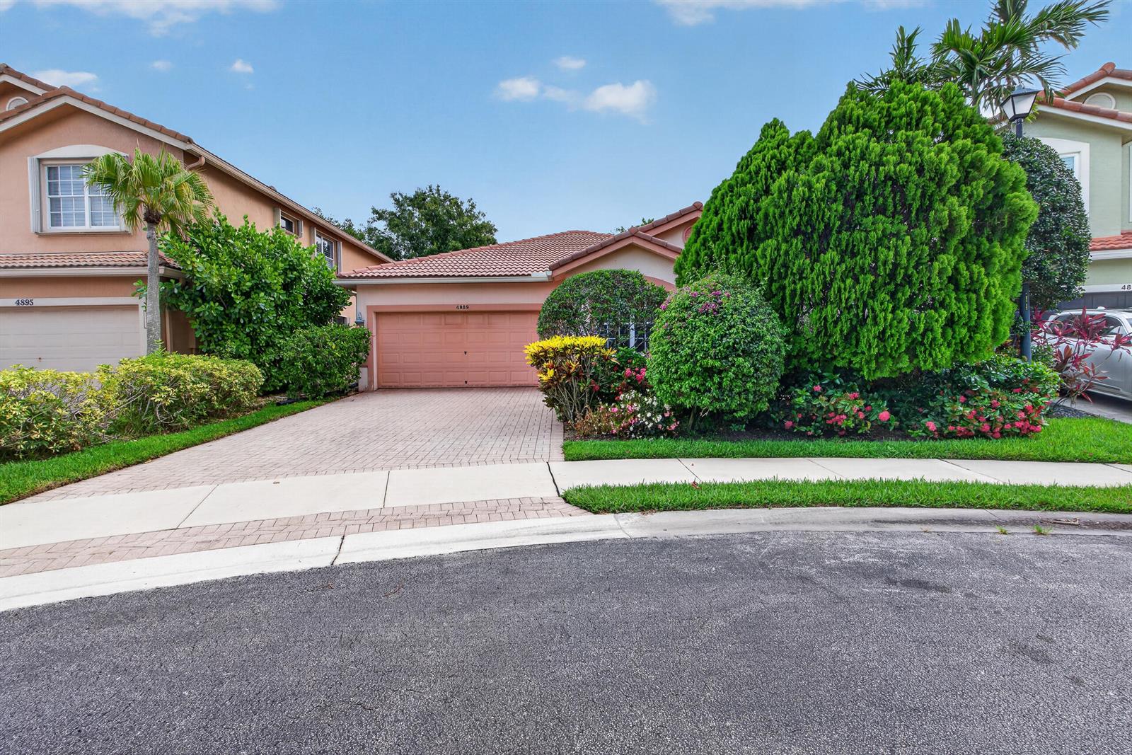 A single-story house with a paved driveway, a two-car garage, and lush landscaping — 4889 N Classical Boulevard, Delray Beach FL 33445, DELRAY BEACH, FL