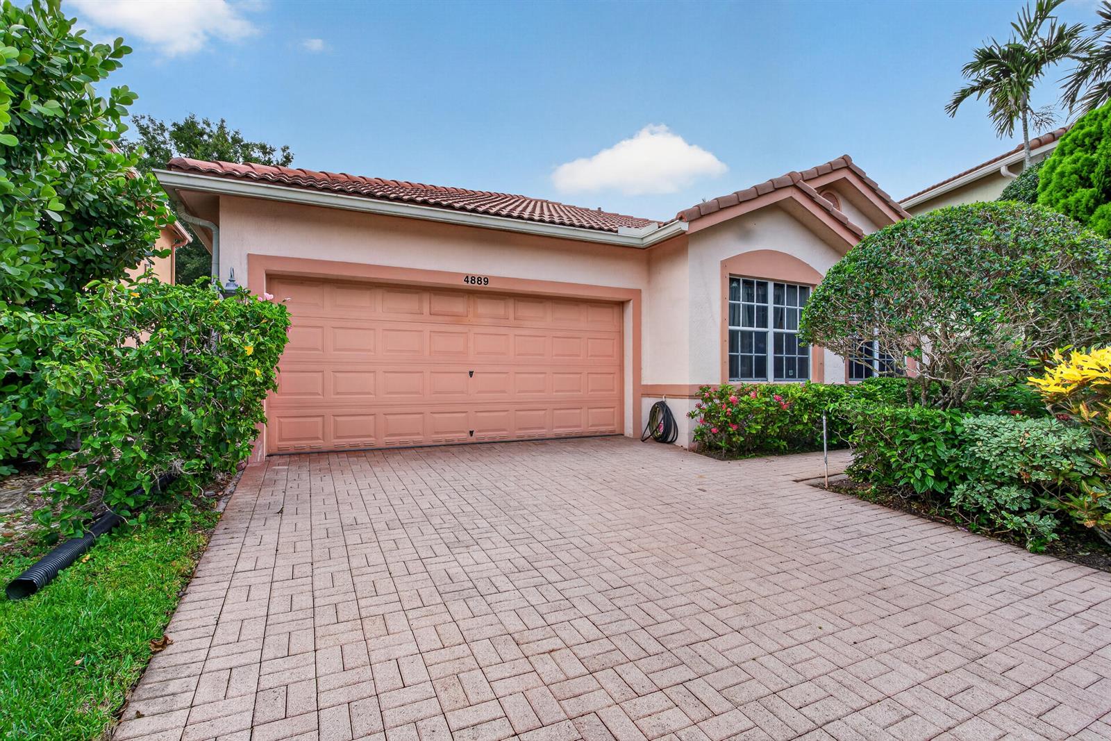 A single-story house with a peach-colored exterior, a two-car garage, and a paved driveway — 4889 N Classical Boulevard, Delray Beach FL 33445, DELRAY BEACH, FL