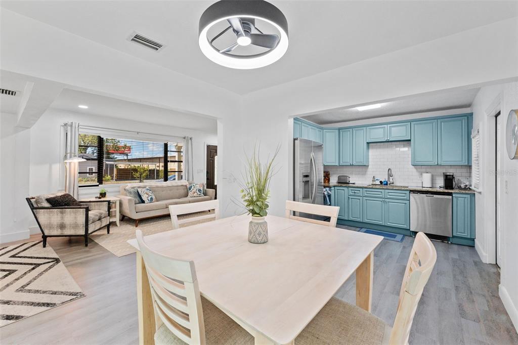 A dining area with a light wood table opens into a living room and kitchen — 3709 W GRIFLOW STREET, TAMPA, FL