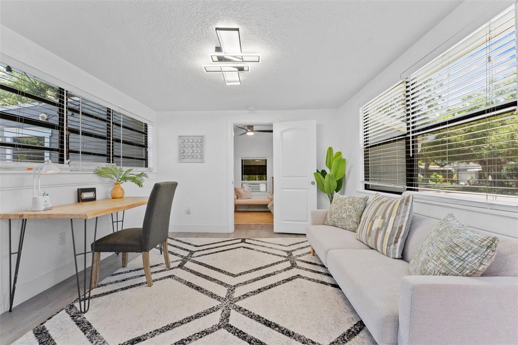 A bright home office features a desk, sofa, geometric rug, and a modern ceiling light — 3709 W GRIFLOW STREET, TAMPA, FL