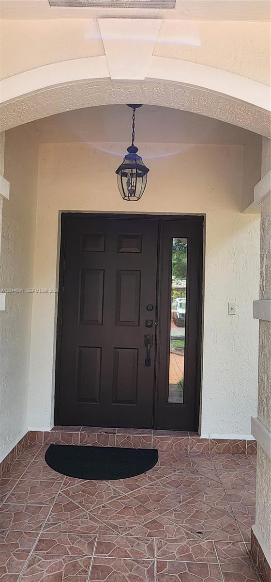A dark brown front door with a side window sits under an arched entryway — 16507 NW 91st Ave, Miami Lakes FL 33018, MIAMI LAKES, FL