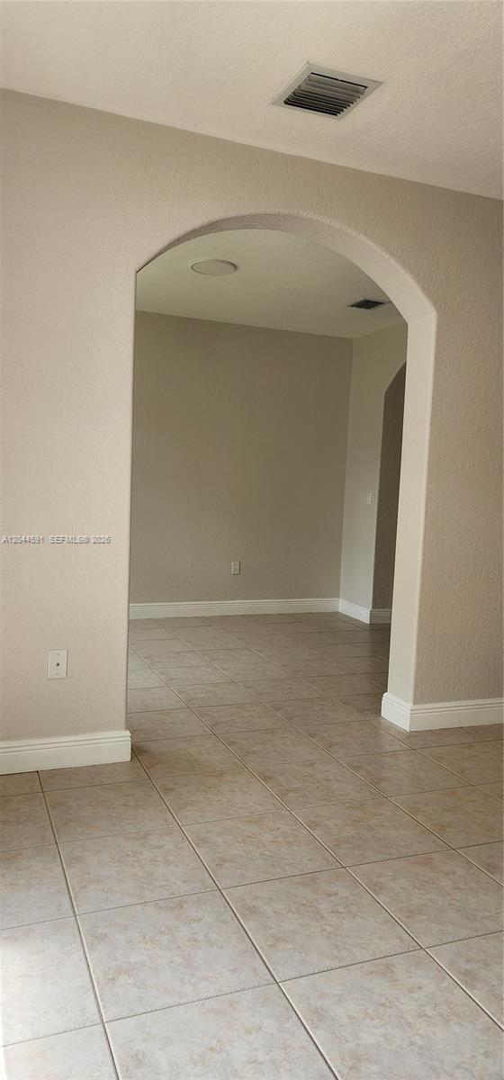 An arched doorway leads from a tiled room into an empty, beige-walled interior space — 16507 NW 91st Ave, Miami Lakes FL 33018, MIAMI LAKES, FL