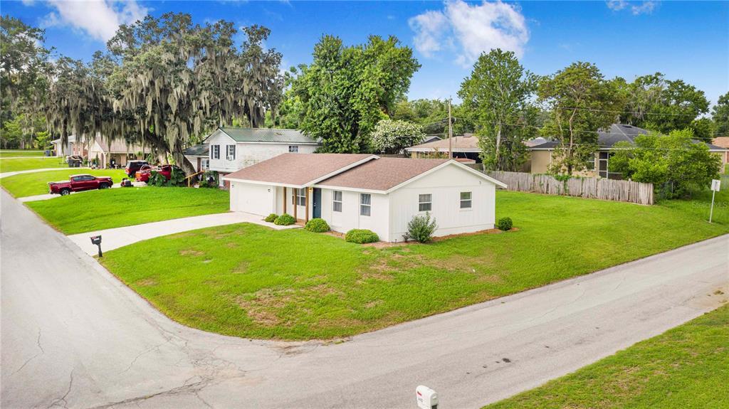 A white, single-story house with a brown roof sits on a corner lot with grass — 4921 SHARON AVENUE, LAKELAND, FL