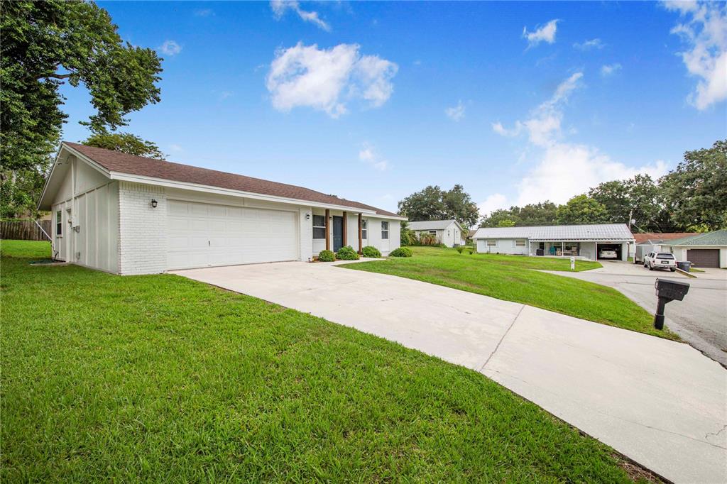 A white single-story house with a two-car garage and a concrete driveway — 4921 SHARON AVENUE, LAKELAND, FL