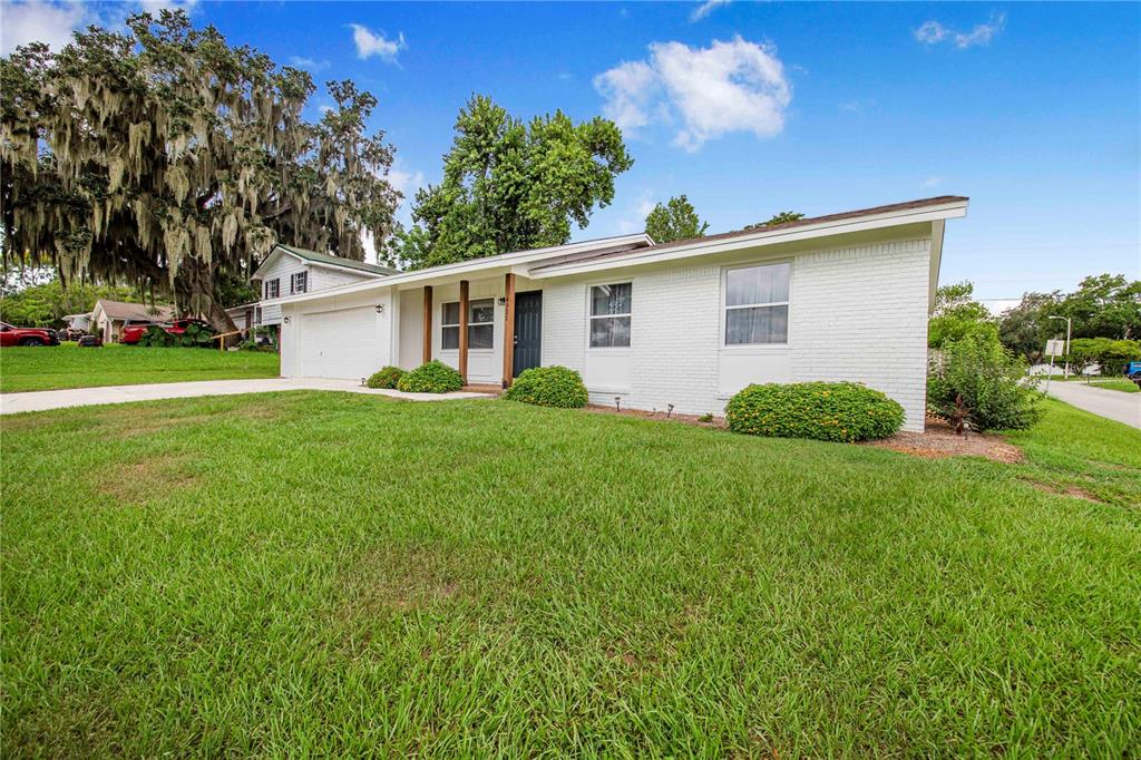 A white brick ranch-style house with a two-car garage sits on a grassy lawn — 4921 SHARON AVENUE, LAKELAND, FL