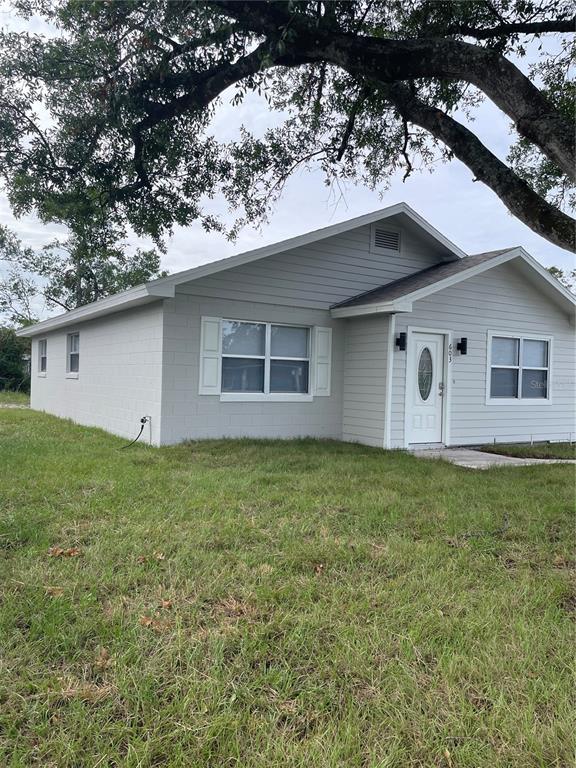 A light gray single-story house with a white front door and a large tree overhead — 603 MAGGIE CIRCLE, WINTER HAVEN, FL