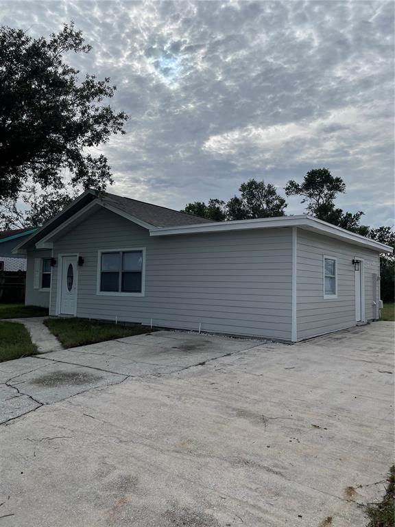 A light gray, single-story house with a concrete driveway and a white front door — 603 MAGGIE CIRCLE, WINTER HAVEN, FL