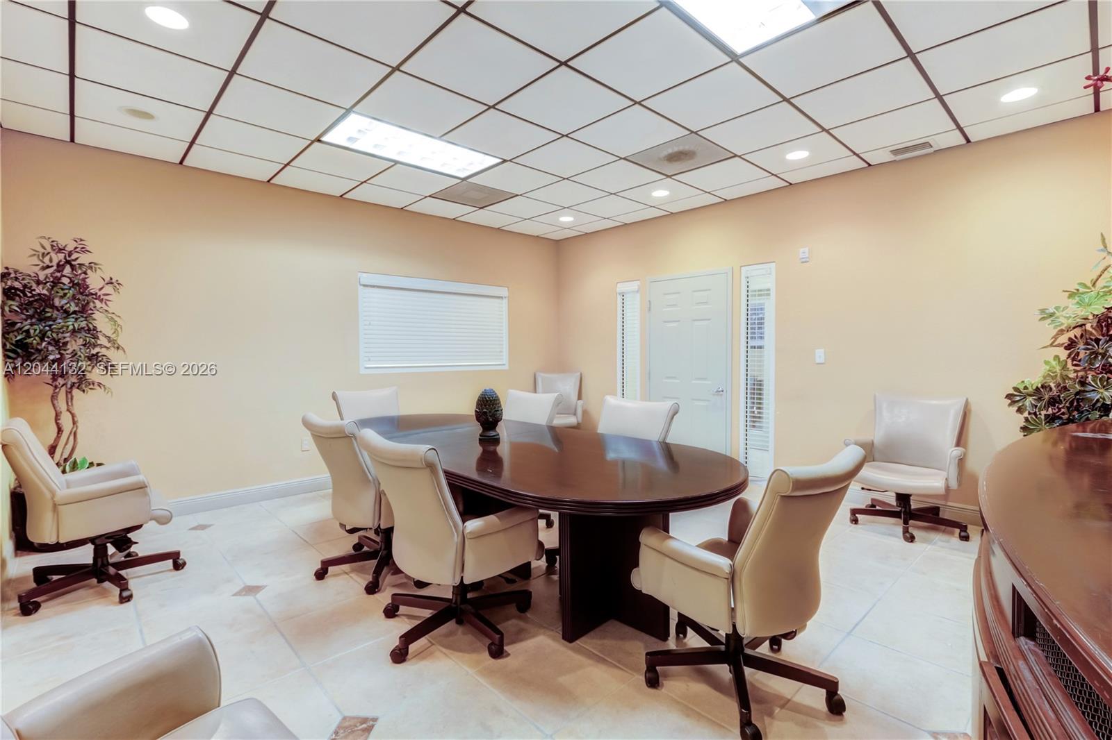 A conference room features a dark oval table, beige chairs, and a drop ceiling — 12150 SW 128th Ct # 138, Miami FL 33186, MIAMI, FL