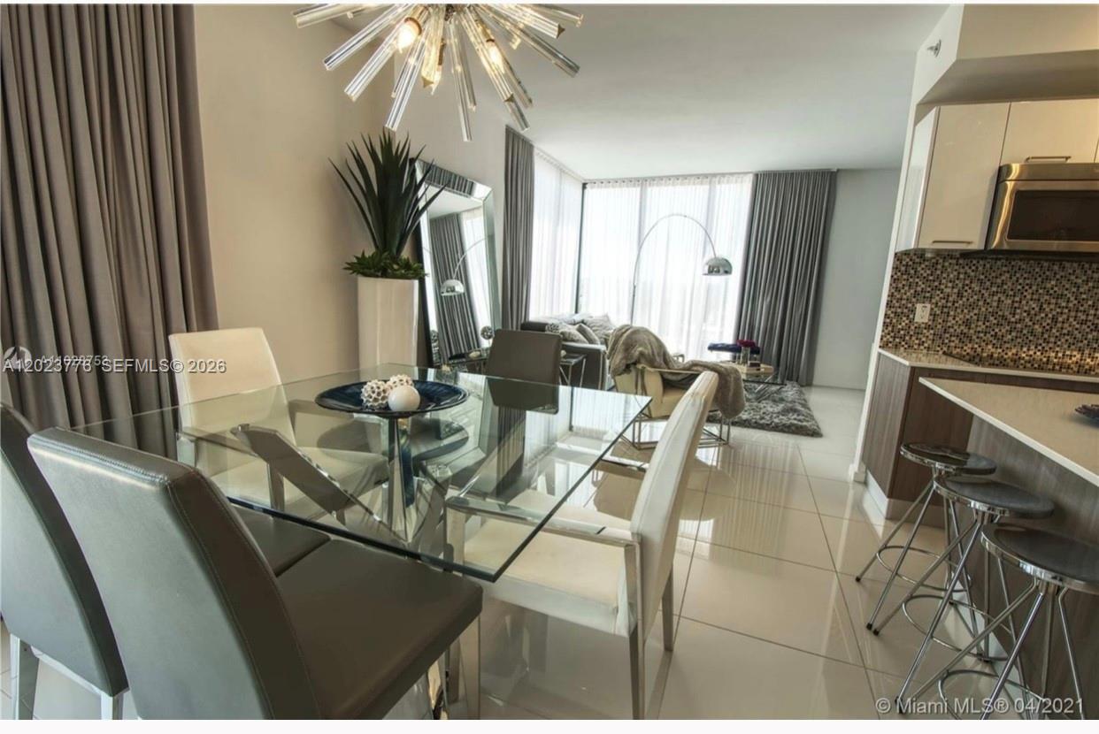 A dining area with a glass table and chairs opens into a living room — 5300 Paseo Blvd   Unit 401 # 401, Doral FL 33166, DORAL, FL