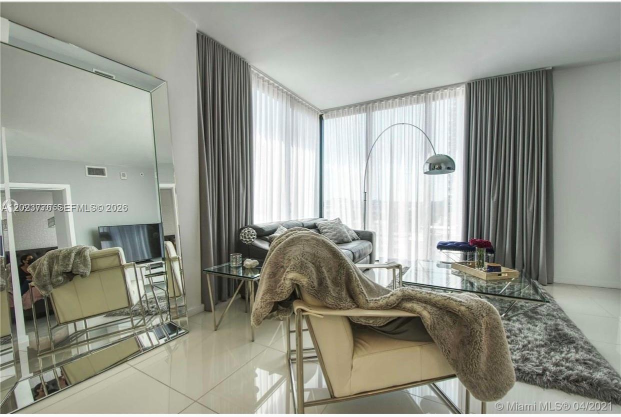 A modern living room features floor-to-ceiling windows, gray curtains, a large mirror, and contemporary furniture — 5300 Paseo Blvd   Unit 401 # 401, Doral FL 33166, DORAL, FL