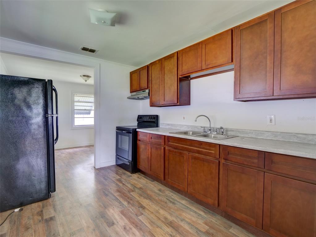 A kitchen features wood cabinets, a black refrigerator, a black stove, and light countertops — 813 NW 5TH STREET, WEBSTER, FL