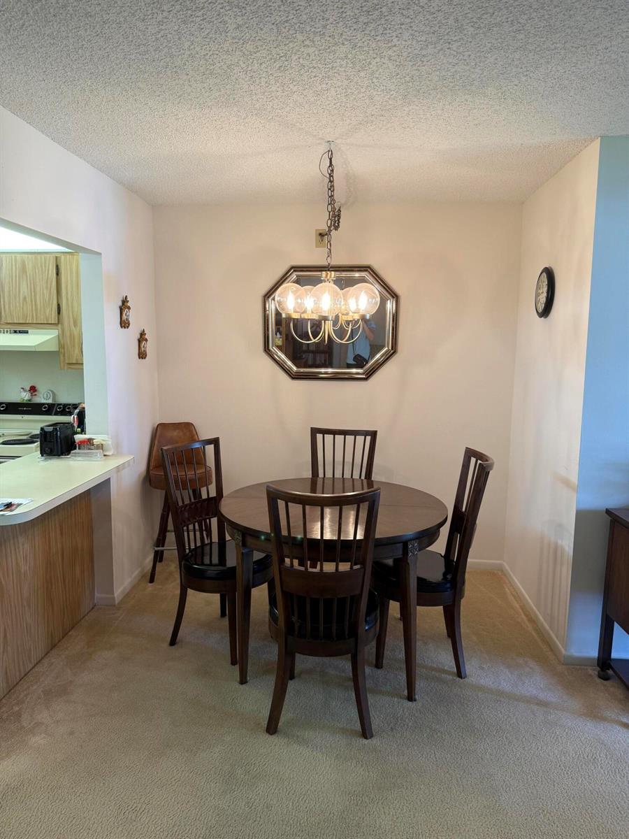 A dining area features a round wooden table with four chairs under a hanging chandelier — 422 Pine Glen Lane # 1, FL 33463, FL