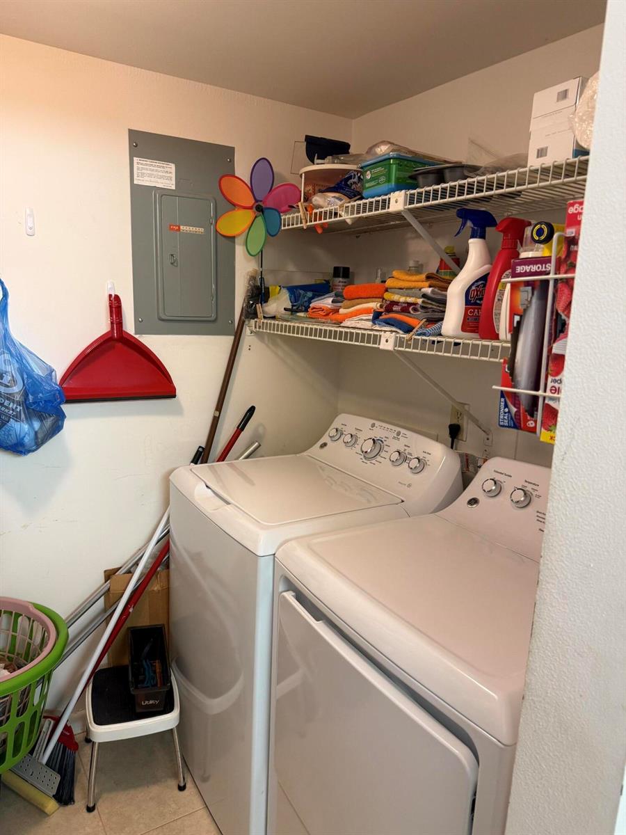 A laundry room features a white washer and dryer, wire shelving, and a circuit breaker panel — 422 Pine Glen Lane # 1, FL 33463, FL