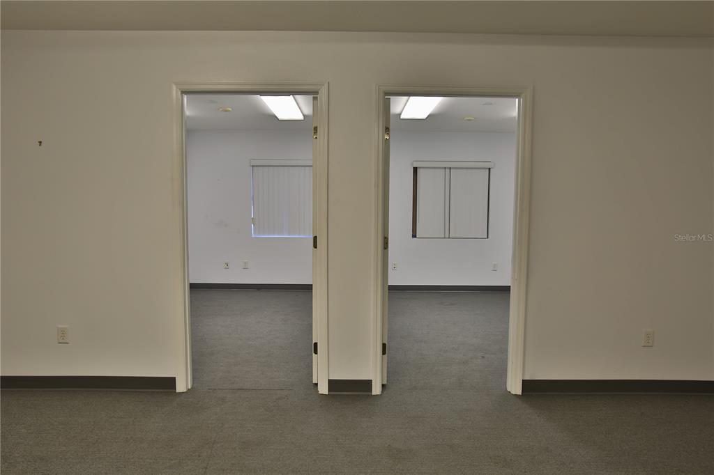 Two doorways open into identical office spaces with gray carpeting, white walls, and fluorescent lighting — 7731 SE 59TH COURT UNIT 300, OCALA, FL