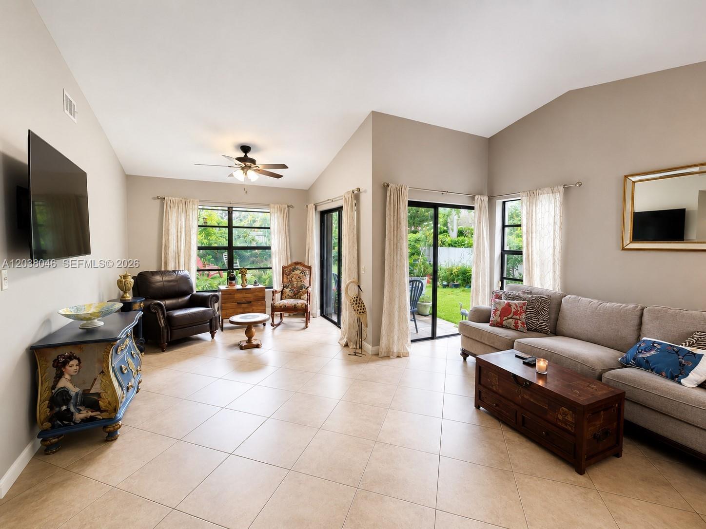 A living room features tile flooring, a vaulted ceiling, a sofa, and sliding glass doors — 13870 Magnolia Ct, Davie FL 33325, DAVIE, FL