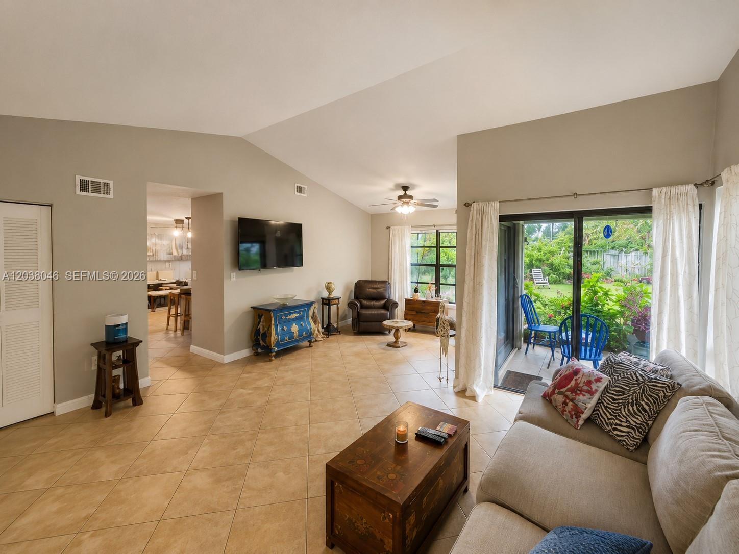 A living room features tile flooring, a vaulted ceiling, a television, and sliding glass doors — 13870 Magnolia Ct, Davie FL 33325, DAVIE, FL