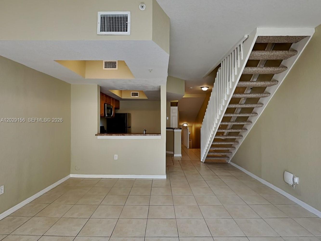 An open living area features tile flooring, a kitchen pass-through, and a carpeted staircase — SUNRISE, FL
