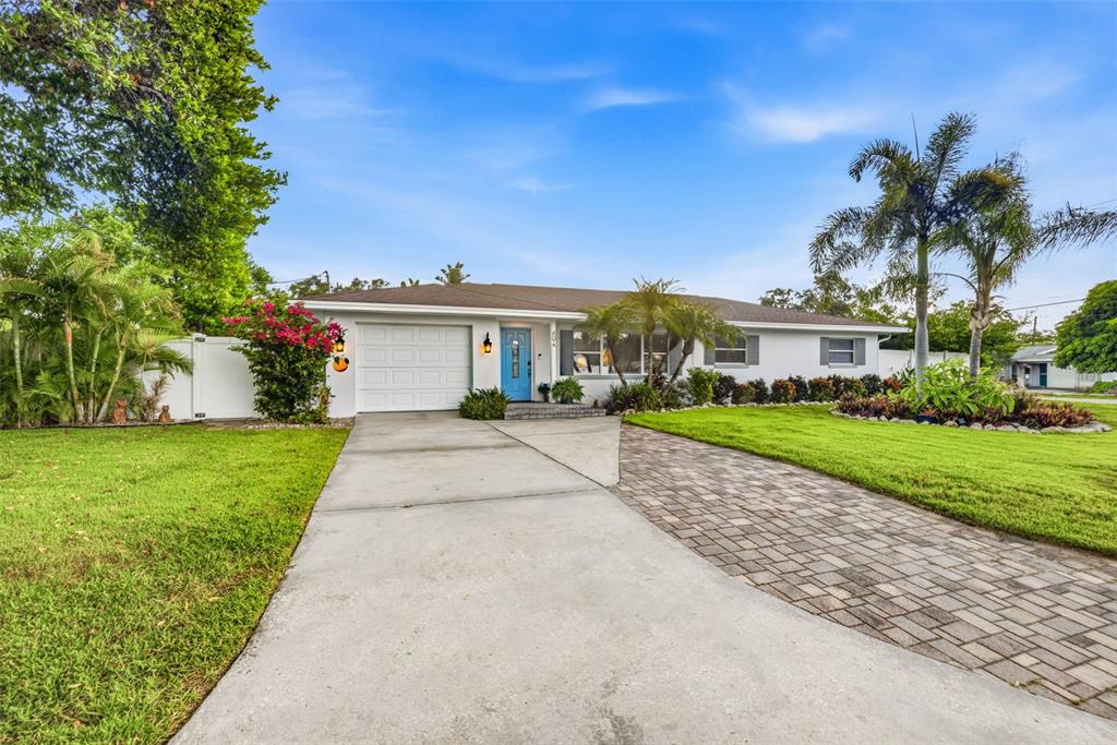A single-story house with a white exterior, blue front door, and a paved driveway — 894 JOAN STREET, DUNEDIN, FL