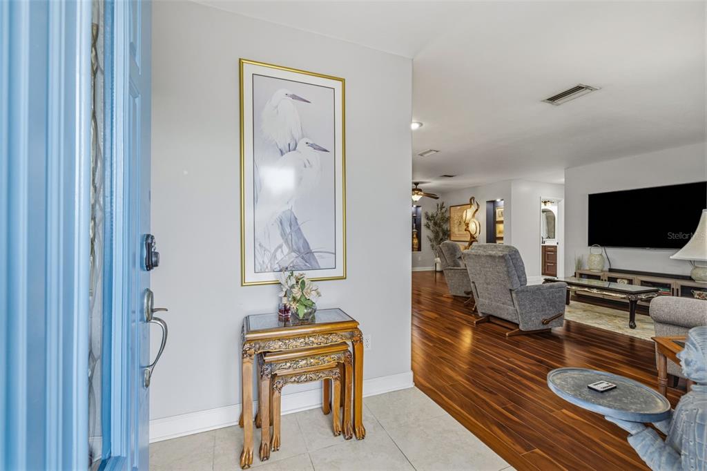 An entryway with a blue door, tiled floor, and nesting tables leads into a living room — 894 JOAN STREET, DUNEDIN, FL