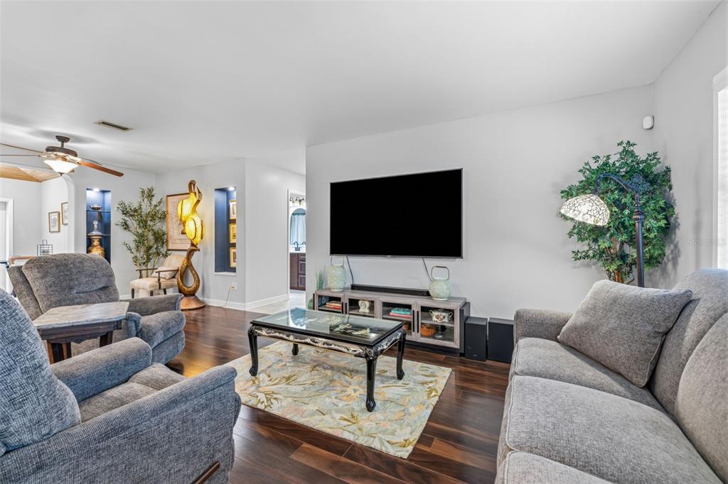 A living room features dark wood floors, a television, a coffee table, and gray furniture — 894 JOAN STREET, DUNEDIN, FL