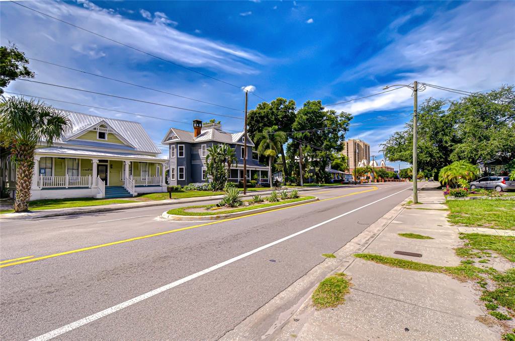 A street view shows two historic houses with porches alongside a road under a blue sky — 408 E PALM AVENUE, TAMPA, FL