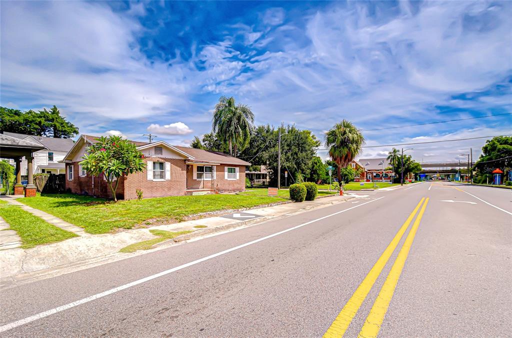 A single-story brick house sits on a corner lot next to a paved road — 408 E PALM AVENUE, TAMPA, FL