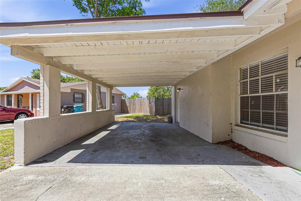 A concrete carport with a white wooden ceiling is attached to the side of a house — 1729 FLORES COURT, ORLANDO, FL