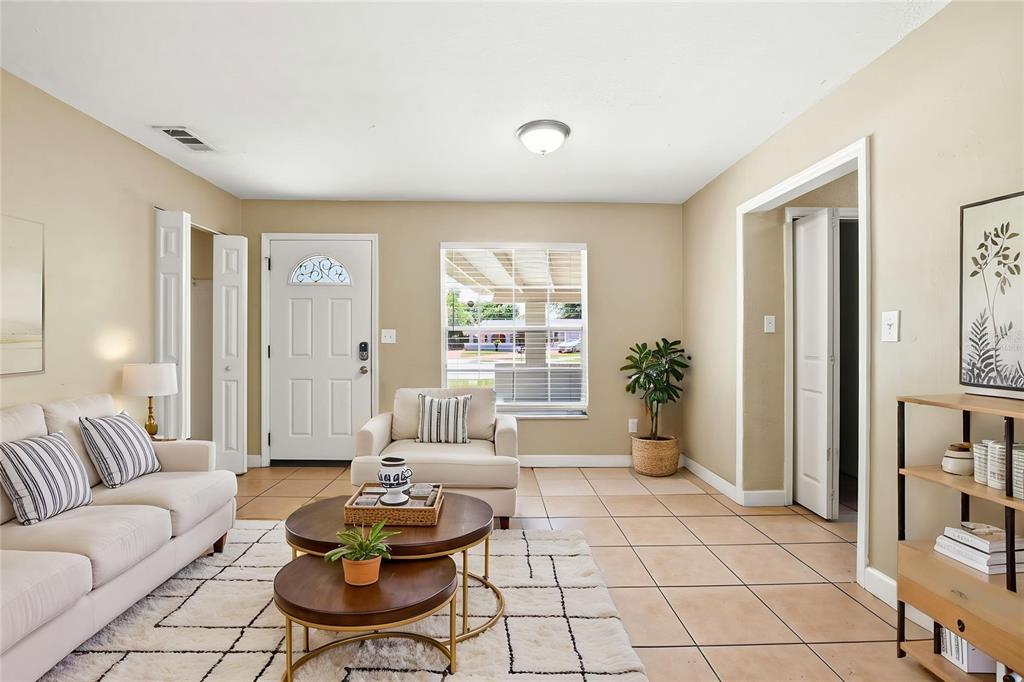 A living room features beige walls, tile flooring, a white front door, and neutral furniture — 1729 FLORES COURT, ORLANDO, FL