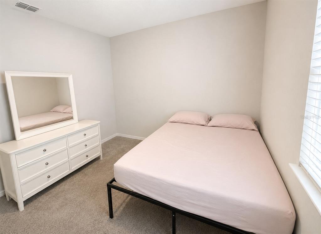 A bedroom features a white dresser with a mirror and a bed with light-colored bedding — 3419 ISLEWOOD COURT, OCOEE, FL