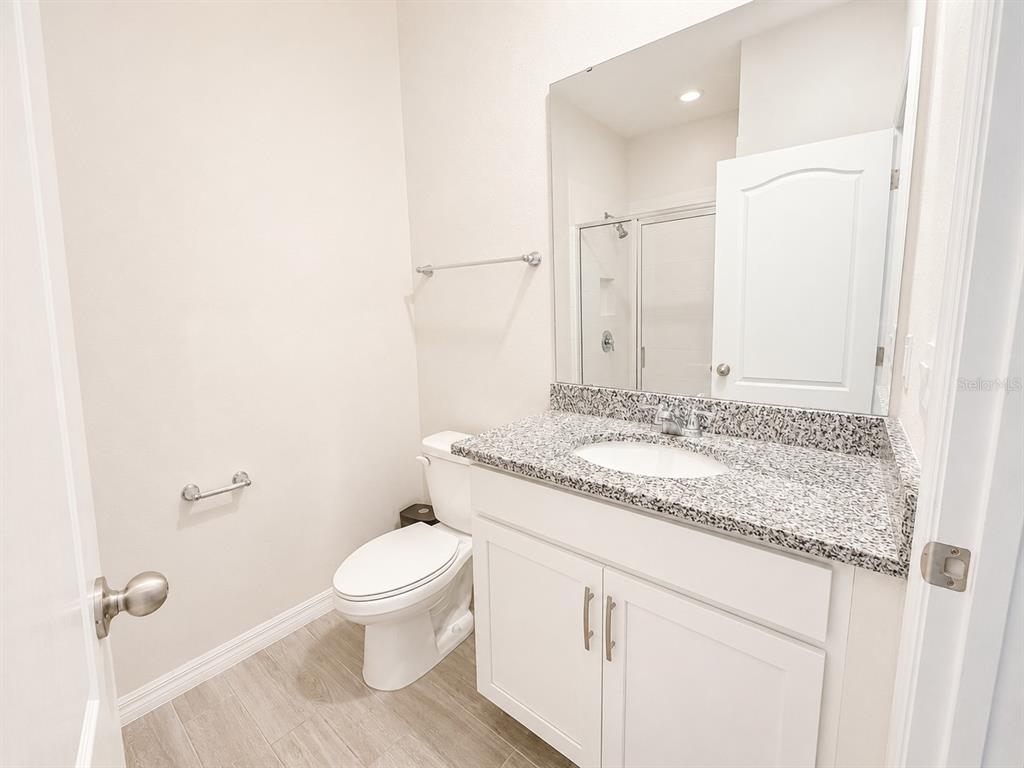 A bathroom features a granite vanity, white cabinets, a toilet, and a mirror — 3419 ISLEWOOD COURT, OCOEE, FL
