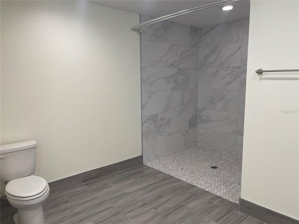 A bathroom features a walk-in shower with marble-look tile, a mosaic floor, and gray flooring — 208 MISSOURI AVENUE, ST CLOUD, FL
