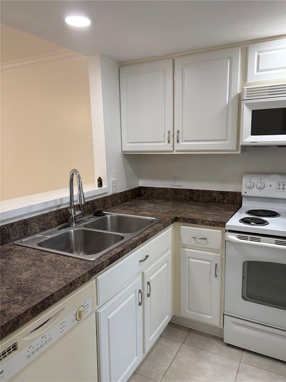 A kitchen features white cabinets, dark laminate countertops, a double sink, and white appliances — 4624 SW 45 LANE, GAINESVILLE, FL
