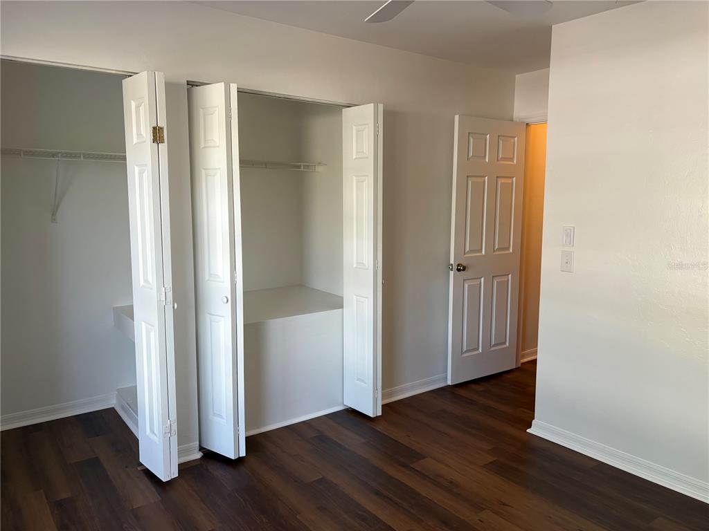 A bedroom features dark wood-look flooring, white walls, a double-door closet, and a doorway — 4624 SW 45 LANE, GAINESVILLE, FL