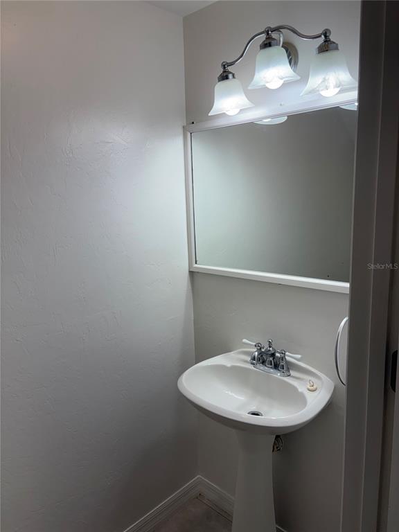 A small bathroom features a white pedestal sink, a wall mirror, and a three-light fixture — 4624 SW 45 LANE, GAINESVILLE, FL