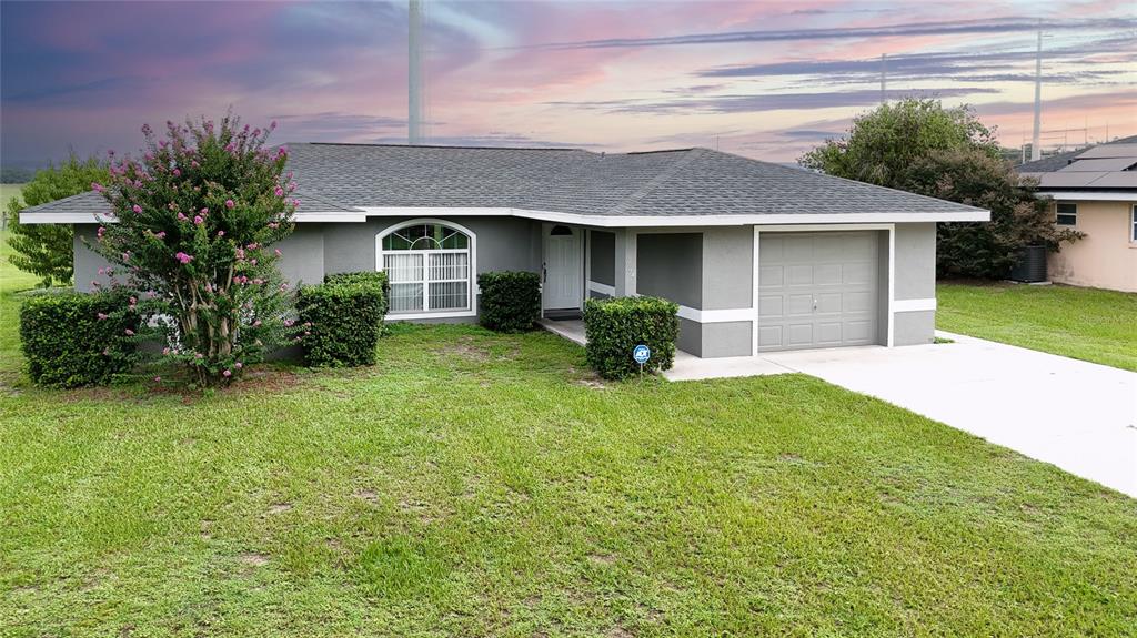 A single-story gray house with a shingled roof, a garage, and a front lawn — 604 BOITNOTT LANE, BUSHNELL, FL