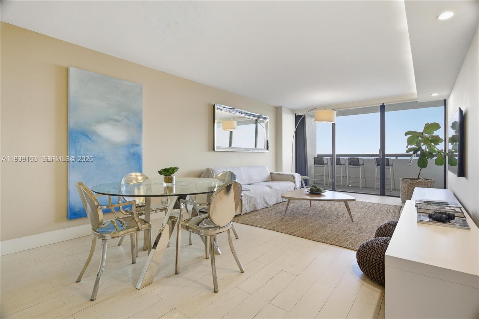 A living and dining area features a glass table, light wood floors, and a balcony — 2555 Collins Ave # 2105, Miami Beach FL 33140, MIAMI BEACH, FL