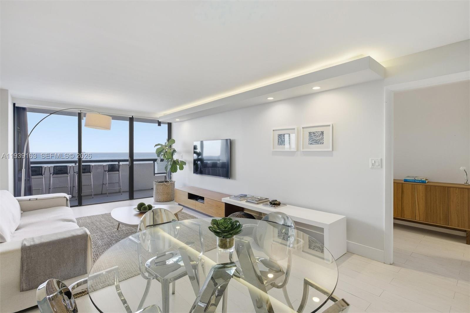 A bright living and dining area features a glass table, white walls, and balcony views — 2555 Collins Ave # 2105, Miami Beach FL 33140, MIAMI BEACH, FL
