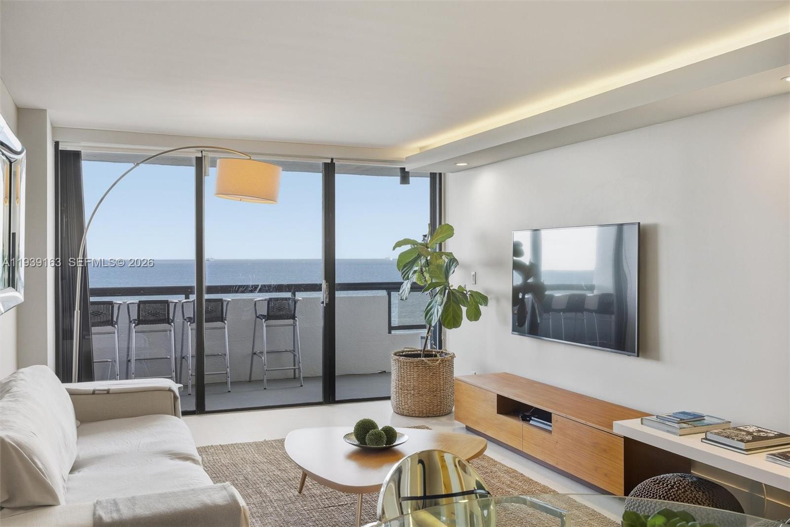 A modern living room features a wall-mounted television, a balcony, and an ocean view — 2555 Collins Ave # 2105, Miami Beach FL 33140, MIAMI BEACH, FL