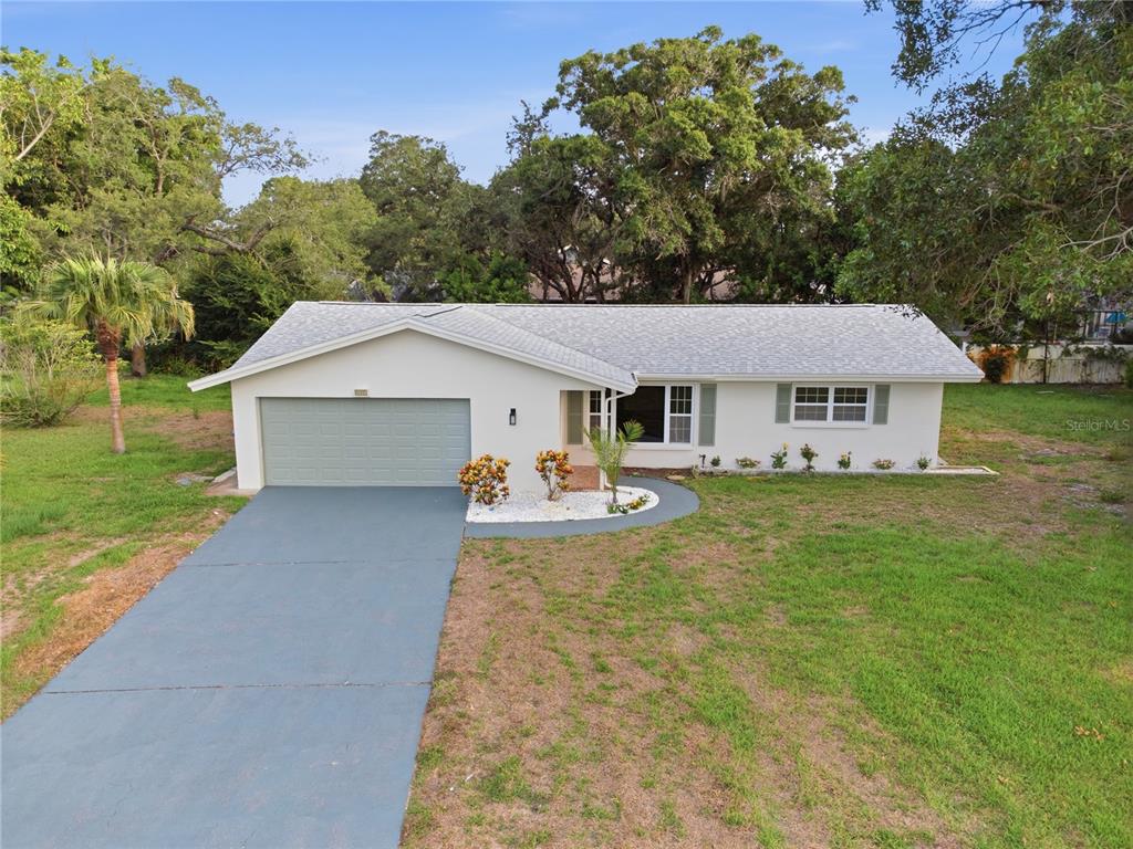 A single-story house with a white exterior, gray roof, and attached two-car garage — 1920 CANADIANA COURT, DUNEDIN, FL
