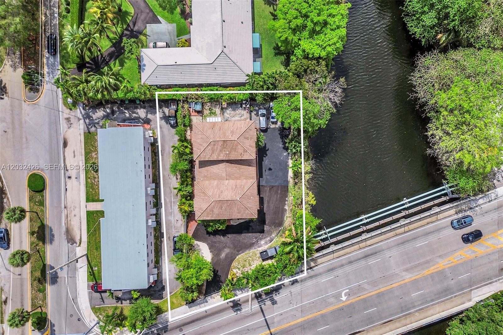 An aerial view shows a residential building with a brown roof and surrounding parking area — 12085 W Dixie Highway, Biscayne Park FL 33161, BISCAYNE PARK, FL