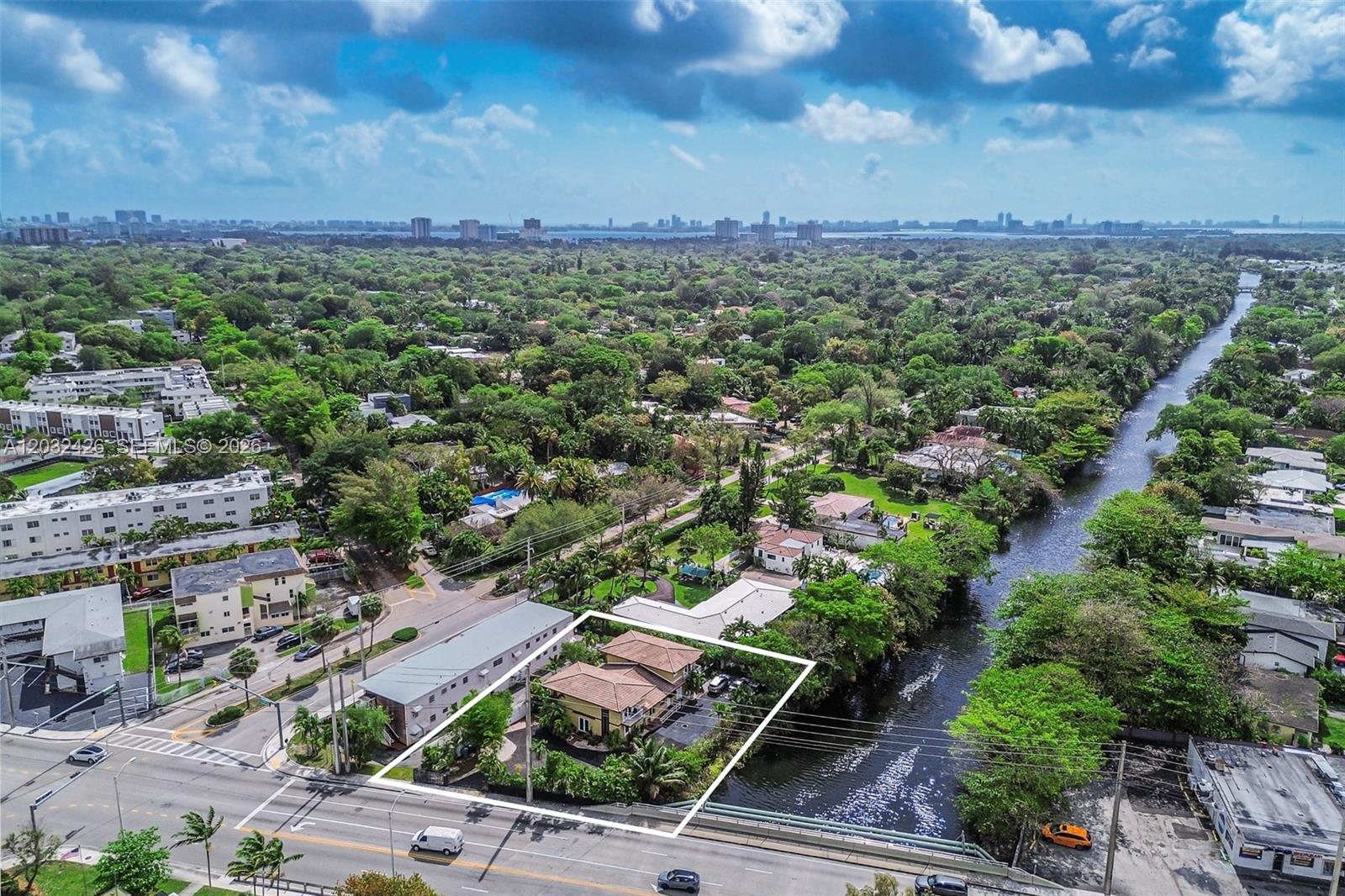 An aerial view shows a house with a tan roof situated next to a canal — 12085 W Dixie Highway, Biscayne Park FL 33161, BISCAYNE PARK, FL