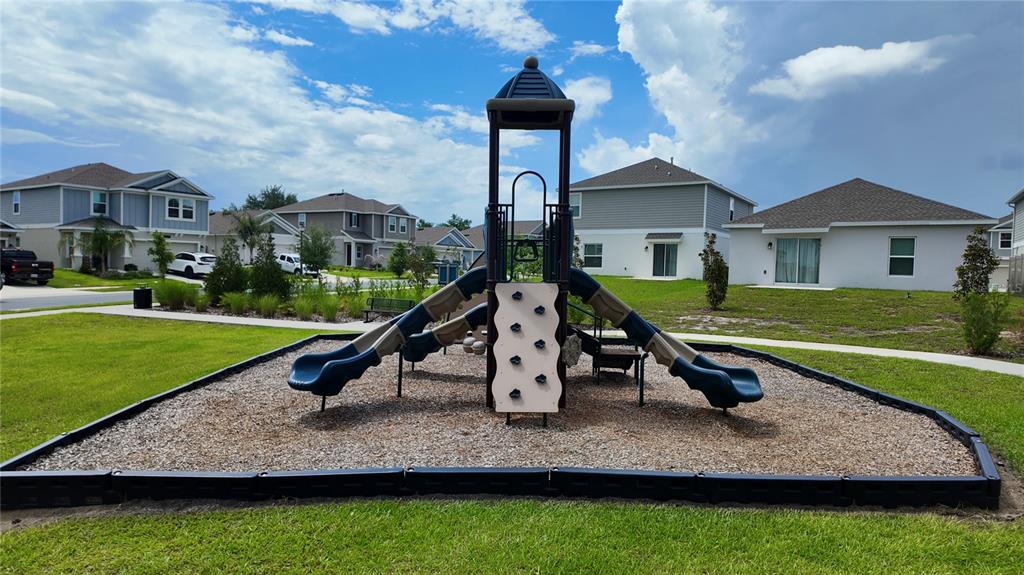 A playground structure with slides and a climbing wall sits on wood chips outdoors — 5620 WINDSONG OAK DRIVE, LEESBURG, FL