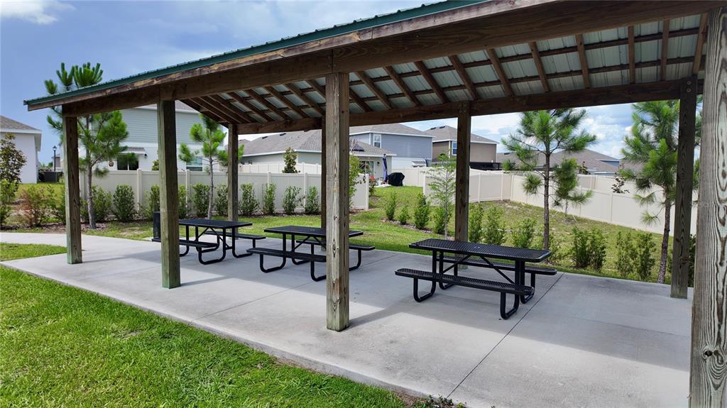 A covered outdoor pavilion features a concrete floor and three black metal picnic tables — 5620 WINDSONG OAK DRIVE, LEESBURG, FL