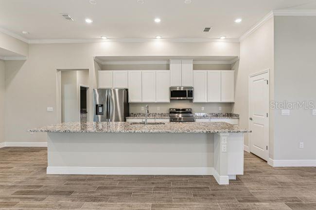A kitchen with white cabinets, stainless steel appliances, and a granite-topped island — 3714 ROMA COURT, PLANT CITY, FL